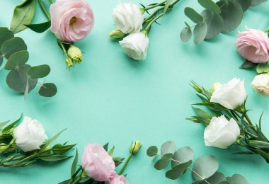 Taze yeşil okaliptüs ile sarmalanmış narin bir beyaz ve pembe çiçek kümesi sakin bir turkuaz yüzeyde durmakta ve dingin bir estetik yaratmaktadır..