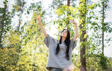 Temiz hava soluyan ve ormanda stresi azaltan genç bir kız. Rüya gibi huzurlu, rahat bir kız doğanın temiz havasını soluyor..