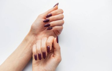 Two hands with beautifully manicured deep purple nails are displayed against a pristine white background. The nails are shaped elegantly, highlighting the artistry of the manicure. clipart