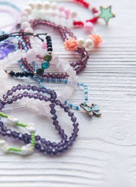 Kırsal ahşap bir yüzeye çeşitli renkli el yapımı bilezikler ve aksesuarlar yerleştiriliyor. Mücevher yapımında yaratıcılık ve zanaatkarlık sergiliyorlar..