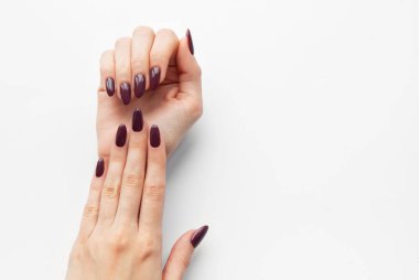 İki el, parlak beyaz bir yüzey üzerinde şık ve zarif bir manikür vurgulanarak, uzun, parlak mor renkli tırnaklarla sergilenir..