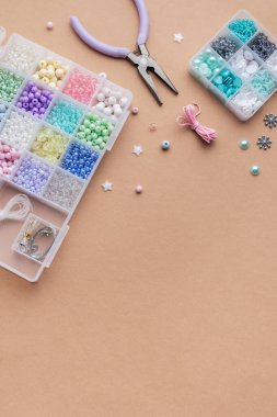 Düz bir yüzeye yayılmış renkli boncuk ve aletlerden oluşan organize bir yapı. Gündüz vakti yaratıcı mücevher yapma projeleri için mükemmel..