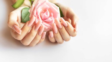 Uzun pembe tırnaklı narin eller güzel pembe bir gül sallıyor, yumuşak ve sakin bir atmosfere zerafet katıyor..