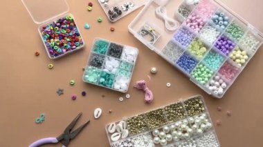 Düz bir çalışma alanında gün ışığında araçlar ve konteynırlarla renkli boncuklarla el işi yapmak