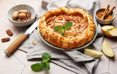 Badem taneleri, nane yaprakları, tarçın ve fındıklı fındıklı seramik bir tabakta servis edilen taze pişmiş elma galetesi.