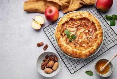 Taze pişmiş elma galetesi serinletici rafta dinleniyor. Yanında bal, ceviz ve taze nane var.