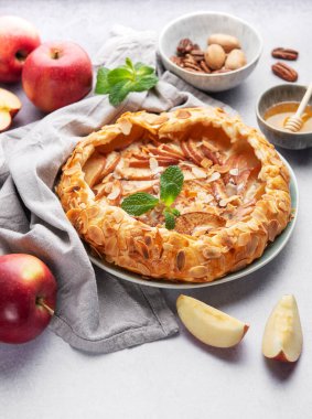 Badem yaprakları ve nane yapraklarıyla süslenmiş, bal ve fındıkla servis edilen açık yüzlü elmalı turta harika bir sonbahar ziyafeti sunuyor.