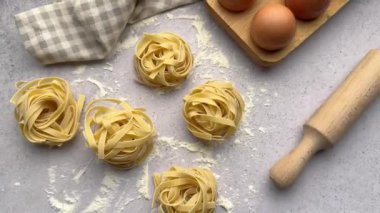 Şef, taze fettucine makarna yuvaları, yumurtalar ve merdane iğnesinden oluşan tezgahın son rötuşlarını yapar.