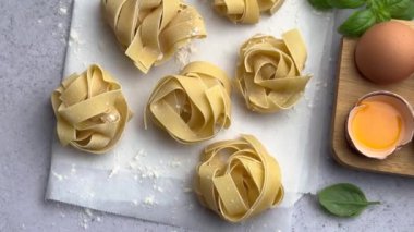 Şef son dokunuşları yumurtalı bir kasenin yanındaki taze makarna yuvasına yapıyor.