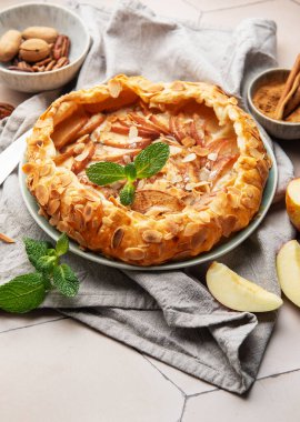 Badem taneleri, nane yaprakları, tarçın ve fındıklı fındıklı seramik bir tabakta servis edilen taze pişmiş elma galetesi.