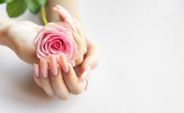 Uzun pembe tırnaklı narin eller güzel pembe bir gül sallıyor, yumuşak ve sakin bir atmosfere zerafet katıyor..