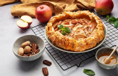 Taze pişmiş elma galetesi serinletici rafta dinleniyor. Yanında bal, ceviz ve taze nane var.