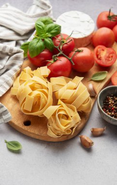 Tahta kesme tahtasına yerleştirilmiş taze malzemeler, makarna yemeği için hazır.