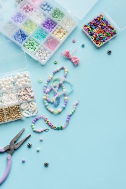 Bir zanaat oturumunda mavi bir yüzeye yayılmış çeşitli boncukların yanı sıra canlı mücevherler yapmak için gerekli araçlar yer alır. Organizatörler boncukları farklı renklerde tutarlar.