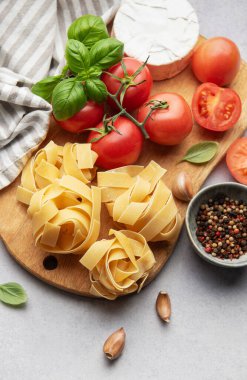 Tahta kesme tahtasına yerleştirilmiş taze malzemeler, makarna yemeği için hazır.