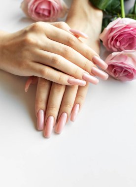 Beyaz arka planda pembe güller olan mükemmel bir pastel pembe manikür.