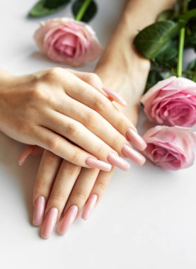 Beyaz arka planda pembe güller olan mükemmel bir pastel pembe manikür.