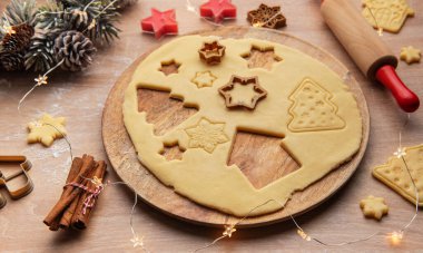 Noel kurabiyesi hamuru şenlikli kesiciler ve dekorasyonlarla hazırlanıyor. Sıcak bir tatil ortamı yaratıyor.
