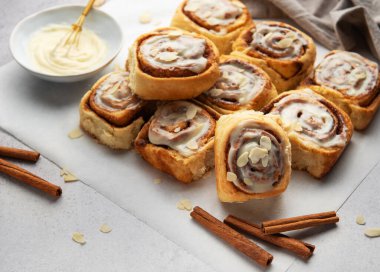 Lezzetli tarçınlı börekler, krem peynirli şekerlemeler ve badem dilimleri serpiştirilmiş tatlı ve cezbedici bir ikram sunar.