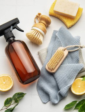 Beyaz fayanslı zemine yerleştirilmiş doğal temizlik ürünleri ve araçları, ev işleri için sürdürülebilir ve ekolojik bilinçli bir yaklaşımı somutlaştırıyor