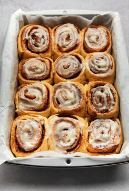 Nefis tarçınlı börekler, mükemmel pişmiş ve kremayla ıslanmış, bir tavada oturmuş, tadını çıkarmaya hazır.