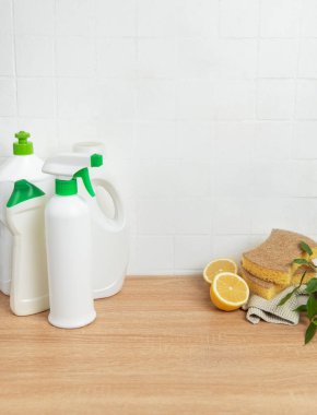 Çevre dostu temizlik ürünleri, süngerler ve limon yarımları beyaz fayansların geri sıçramasına karşı ahşap tezgahta oturur ve doğal temizlik çözümlerini teşvik eder.