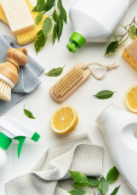 Beyaz yüzeyde doğal temizlik ürünleri, limon dilimleri, fırçalar ve süngerler ekolojik bilinç temizleme rutinini destekliyor