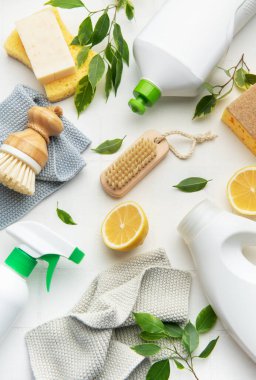 Beyaz yüzeyde doğal temizlik ürünleri, limon dilimleri, fırçalar ve süngerler ekolojik bilinç temizleme rutinini destekliyor