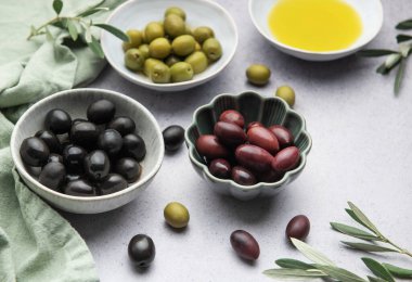 Zeytin yağı ve zeytin dallarıyla marine edilmiş zeytinlerin çeşitliliği bir Akdeniz mutfak sahnesi yaratır.