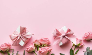 Pembe güllerin ve pembe arka planda saten kurdelelerin bulunduğu hediye kutularının şenlikli düzenlemeleri. Özel durumları kutlamak için mükemmel.