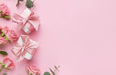 Pembe güllerin ve pembe arka planda saten kurdelelerin bulunduğu hediye kutularının şenlikli düzenlemeleri. Özel durumları kutlamak için mükemmel.