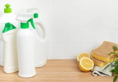 Çevre dostu temizlik ürünleri, süngerler ve limon yarımları beyaz fayansların geri sıçramasına karşı ahşap tezgahta oturur ve doğal temizlik çözümlerini teşvik eder.