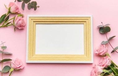 Pembe güller ve okaliptüs yapraklı ahşap çerçeve pembe arka planda romantik bir ortam yaratır. Sevgililer Günü projeleri için mükemmel.