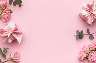 Pembe güller ve okaliptüs yaprakları pastel pembe bir fon üzerine dizilmiş.