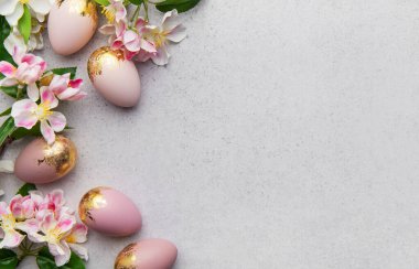 Altın folyo süslemeli ve bahar çiçekli zarif pembe paskalya yumurtaları gri arka planda güzel bir sınır oluşturur. Bayram kutlamaları için mükemmel.