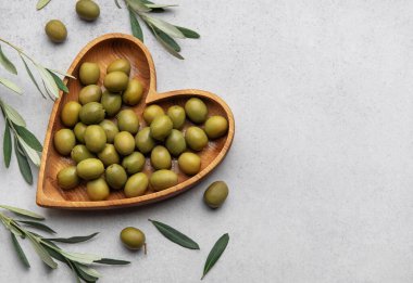 Taze yeşil zeytinler, zeytin dallarıyla süslenmiş güzel ahşap kalp şeklinde bir kasede servis edilir.