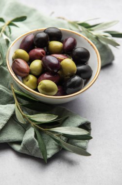 Zeytin dallarıyla dolu bir kasede renkli zeytinler servis edilir. Akdeniz aperatifi oluşturur.