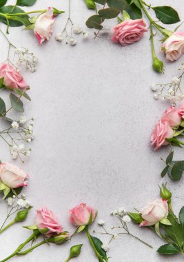 Pembe güller, okaliptüs yaprakları, ve bebek nefesi çiçekleri gri arka planda güzel bir çerçeve oluşturuyor, zarafet katmak için mükemmel.