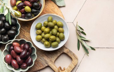 Tahta bir tahtanın üzerinde sunulan zeytinlerin çeşitliliği, Akdeniz lezzetlerinin genel görünümünü oluşturur