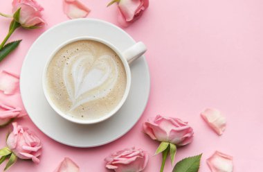 Bir fincan kapuçino ve pembe arka planda pembe güller. Aşkı, sevgililer gününü ya da anneler gününü kutluyorlar.