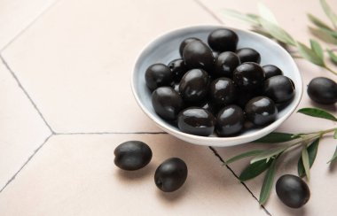 Zeytin dalıyla bej bir kapta siyah zeytin, Akdeniz mutfağı sahnesi yaratır.