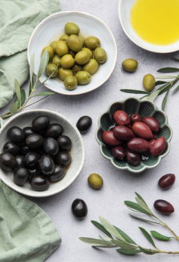 Zeytin yağı ve zeytin dallarıyla marine edilmiş zeytinlerin çeşitliliği bir Akdeniz mutfak sahnesi yaratır.