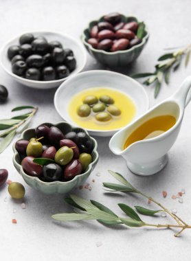 Çeşitli zeytinler, zeytinyağı ve zeytin dalları Akdeniz mutfağı sahnesi oluşturur