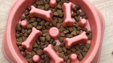 Kuru köpek maması yavaş yavaş kayboluyor ahşap bir yüzey üzerindeki yavaş besleyici kaseden.