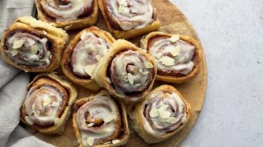 Krem peynirli krema ve badem gevreğiyle kaplanmış taze pişmiş tarçınlı rulo.