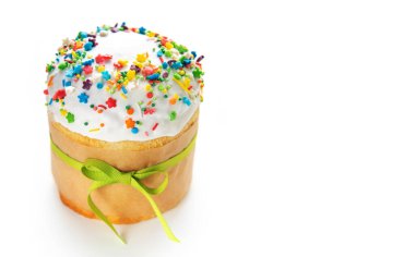 Lezzetli paskalya pastası, beyaz kremalı ve renkli serpilmiş, yeşil bir kurdeleyle bağlanmış, baharı ve kutlamaları simgeliyor.