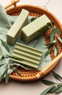 Doğal zeytin sabunları ve zeytin dalları dokunmuş bir tepside sergilenerek organik banyo ürünlerini tanıtıyorlar.