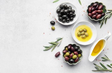 Çeşitli zeytinler, zeytinyağı ve zeytin dalları Akdeniz mutfağı sahnesi oluşturur