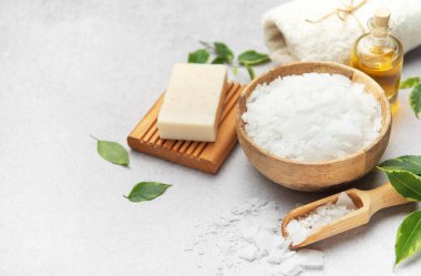 Magnesium bath flakes, soap, towel, and essential oil are arranged on a gray surface, evoking a tranquil spa ambiance