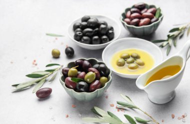 Çeşitli zeytinler, zeytinyağı ve zeytin dalları Akdeniz mutfağı sahnesi oluşturur